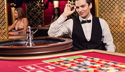 Een croupier leunt op een Evolution roulette tafel.