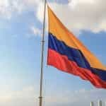 Vlag van Colombia die op mast over hemel met wolken zwaaien.