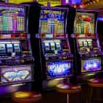 Drie felgekleurde speelautomaten in een casino.